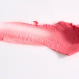 Smuga różowej pomadki, która może zawierać methylparaben, na białym tle.