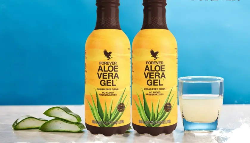Dwie butelki Forever Aloe Vera Gel, szklanka z napojem i liście aloesu. Wiele pozytywnych forever aloes opinie potwierdza jego jakość.