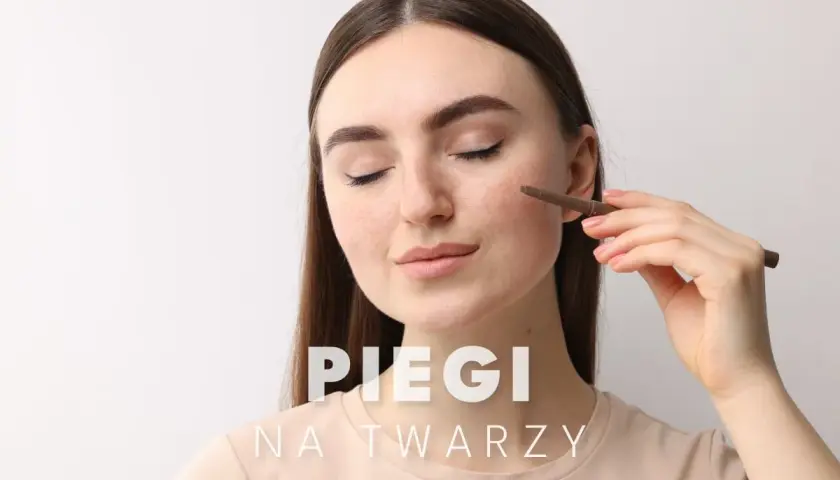 Kobieta z piegami na twarzy delikatnie poprawia makijaż.