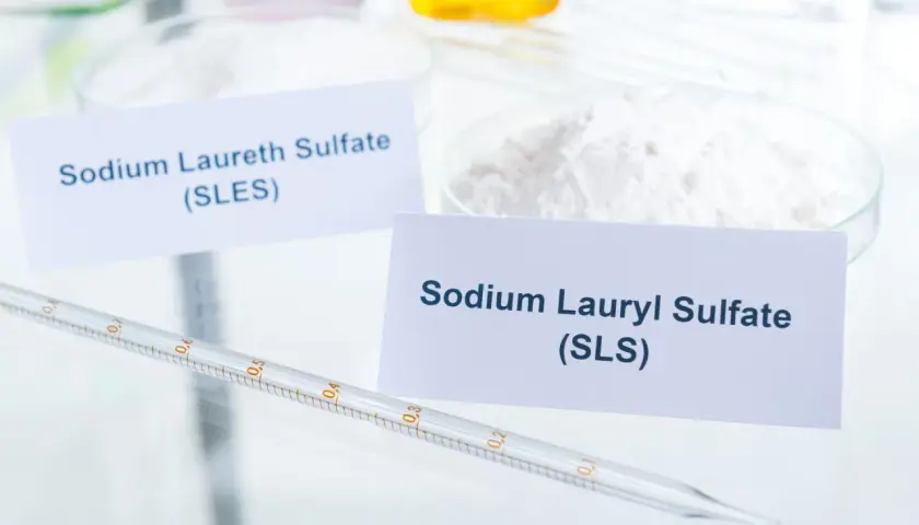 W laboratorium białe proszki: Sodium Laureth Sulfate (SLES) i Sodium Lauryl Sulfate (SLS). Pipeta z podziałką leży obok.