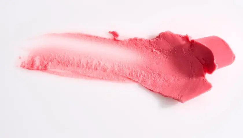 Smuga różowej pomadki, która może zawierać methylparaben, na białym tle.